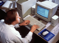 A blind man works at a computer using a screenreader.