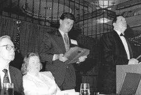 Don and Betty Capps look on while Congressman Ehrlich hols the plaque and Allen Harris addresses the audience.