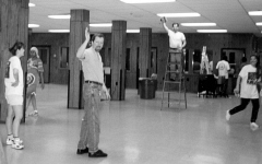 Liane Sudbrook looks on as Joe Miller, standing, and Craig Gildner, on a ladder, wave at the camera.