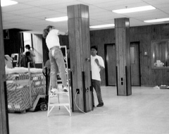Lauri Shropshire on a ladder and Curtis Chong on the floor clean and buff a paneled pillar.