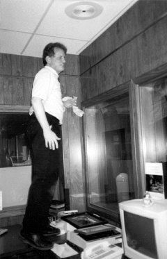 President Maurer stands on a desk in one of the offices in the Materials Center preparing to wash a window.