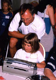 Rob Sweeney of California works with daughter Kyra on a Braillewriter at the Braille Carnival