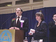 Michael Brands addresses the banquet audience while Peggy Elliot looks on.