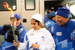 Lori Pierce; and Olympic security official(left); and Ted Clark (right); the support runner for Lori's segment of the run, look at the Olympic torch that Lori is holding.
