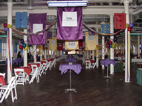 This picture shows the huge room on the third floor of the National Center for the Blind, which has been transformed by hanging banners with sponsor names, balloons, crepe paper streamers, and elegantly draped tables.  Th effect is very festive.