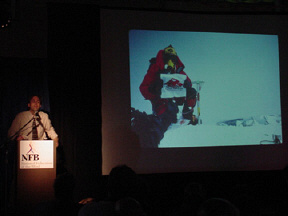 Erik Weihenmayer describes his Everest climb to a spellbound audience.  At the right on a large screen can be seen a slide show of the now famous picture of Erik on top of Mt. Everest holding up the expedition banner.