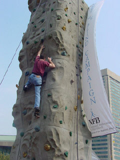 Federationist Jason Ewell spread-eagled part way up the climbing wall.
