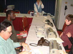 The Mercury Room is almost always busy.   Here, Sandy Halverson takes a phone call at her post near the boxes of congressional reporting cards.   John Antonacci in the foreground gives a report.