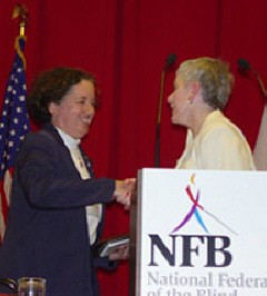 Dr. Sheila Amato shakes hands with Sharon Maneki at the podium.