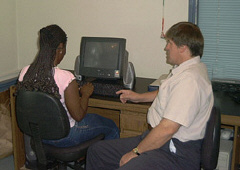 Al Spooner works with Kotumu Kaamara from Liberia at a computer station.