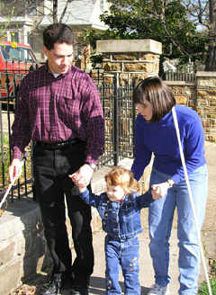 Using their white canes, Eddie and Maria Bell go for a walk with daughter Victoria between them.