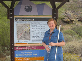 Judith Tunell stands at the entrance of the hiking trail named to honor her.