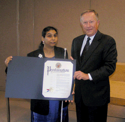 Yasmin Reyazuddin from the Sligo Creek Chapter of the NFB of Maryland receives a Disability Mentoring Day proclamation by Montgomery County chief administrative officer Bruce Romer. Yasmin helped place three young blind people in mentoring positions for the day.  Placements were at Verizon, Computer Technology Associates, and the Montgomery County Department of Aging.