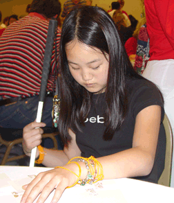 Anne Naber (MN) is pictured matching scents in cups to Braille words on a card at the Braille Carnival.
