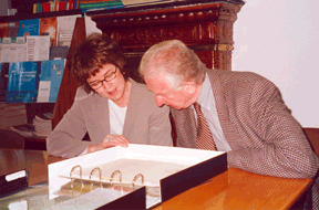 A man and woman lean over an archival box of documents.