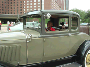 A young Federationist enjoys pretending to drive a 1930 Ford.