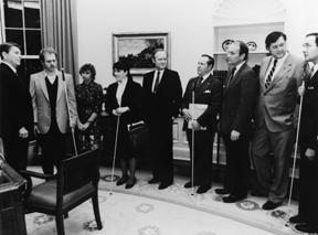In 1983 President Reagan met with Bill Morgan and his wife, legislators from Idaho, and leaders of the National Federation of the Blind in the Oval Office. Pictured here (left to right) are President Ronald Reagan, Bill Morgan, Lynda Morgan, then-NFB-of-Idaho-President Ramona Walhof, Senator Steven Symms, NFB President Kenneth Jernigan, Senator Larry Craig, Representative George Hansen, and NFB Director of Governmental Affairs James Gashel.