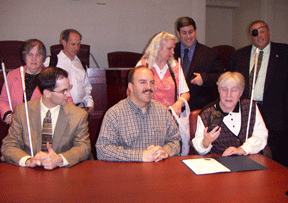 Chris Zimmerman, Arlington County board chairman (Virginia), looks on as Seville Allen demonstrates the Kurzweil�National Federation of the Blind Reader during a White Cane Safety Day Proclamation presentation. Also pictured, from left to right, are Tracy Soforenko (seated), Gerry Sanchez, Alan Schlank, Billie Ruth Schlank, Larry Povinelli, and Charlie Brown.