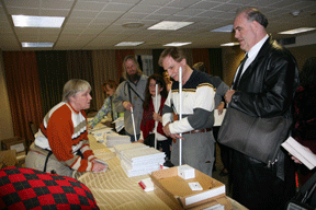 In the Mercury Room Seville Allen of Virginia takes appointment times down in Braille from Shawn Jacobson of Maryland. Beside Shawn, waiting his turn, is Gary Ray of North Carolina, followed by Corinne Vieville and Bill Haley of Oregon.