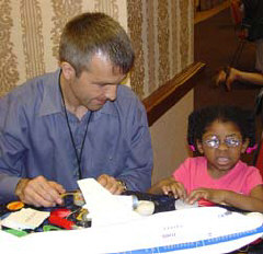 Astronomer and DePaul University professor, Bernhard Beck-Winchatz, finds that blind people of all ages at the NFB convention are interested in astronomy.   Above, he helps preschooler Mikaella Besson learn about planets.