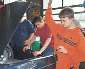 Nikos Daley and David Venit prepare to locate the spare tire in the trunk of one of Stan Griffin's cars.