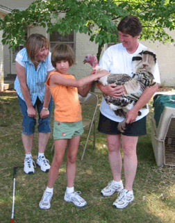 Mom watches as her daughter pets a turkey held by a volunteer.