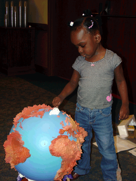 Small child touches a tactile globe.