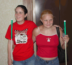 Two young girls stand with arms around each other.