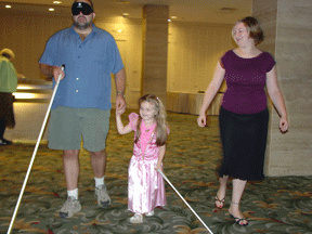 Steve Walker and his daughter Anna get a cane travel lesson from Kristen Simms at the Cane Walk.