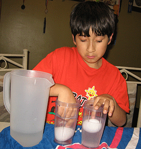 Alex reaches into two glasses to discover how high each egg floats.