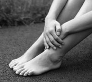 Hands crossed above the feet of a woman.