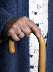 A senior's hand rests on a walking cane.