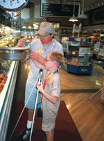 A father and son shop for produce with their canes in hand.
