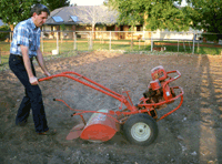 A man tilling a garden.