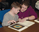 A young blind boy and his mother read a Braille/print book with tactile graphics.