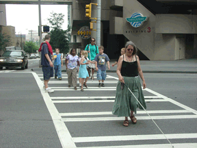 Elizabeth Rousseau-Rooney (OR) leads a group of NFB Campers through an intersection during a camp field trip.
