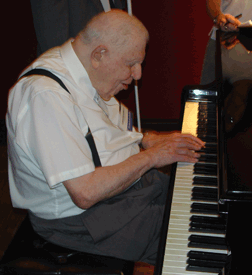 An afternoon thundershower drove the 2006 barbeque indoors. Here, Dr. Abraham Nemeth plays the piano at an impromptu barbeque sing-along.