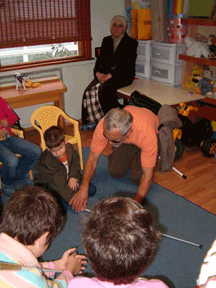 Robert Leslie Newman teaches several students how to sweep the long cane across the floor to find a dropped object.