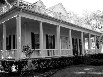 A historic home with a wrap around porch.