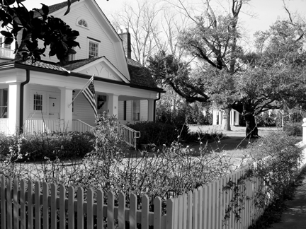 A home with a large yard and white picket fence.