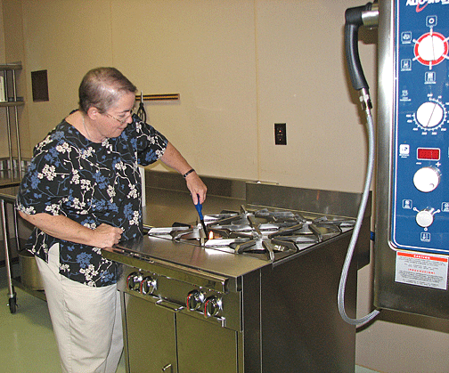 Mary Ellen Thompson lights the pilot light of the stovetop.