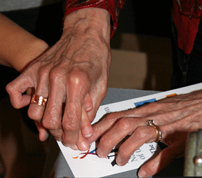 Dolores Reisinger&rsquo;s hands guiding a student&rsquo;s hands over Braille characters