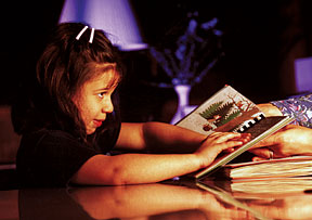 A young girl reading Braille