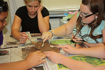 Students use brushes to get a better look at the footprint.