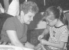 Photo of Diane McGregor helping Nichelle 

    Bryson make a craft. (20429 bytes)