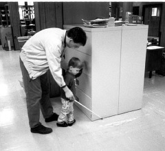 David Small shows his son, Benjamin, how he can use the cane to find obstacles.   This impromptu lesson takes place in the Materials Center of the National Center for the Blind, headquarters of the National Federation of the Blind. 