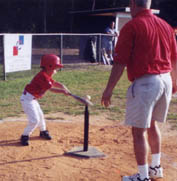 Ryan swings toward the ball as his dad, Mike, cheers him on.