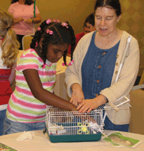 MarChe Daughtry, age 9, (Virginia), attends a workshop on pets and pet care where, among other hands-on activities, she gets to pet a parakeet, or �budgee� as native Australian Heather Fields calls her favorite pets. 