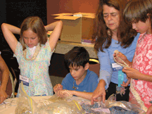 Here, session leader Corinne Vieville works with Camille Blair (Utah) and Stephen Toth, age 10, (Louisiana) to create beaded jewelry. 