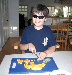 Vejas slicing fruit in order to prepare the fruit salad. He�s learned that those that help with the cooking, can help themselves to the eating.